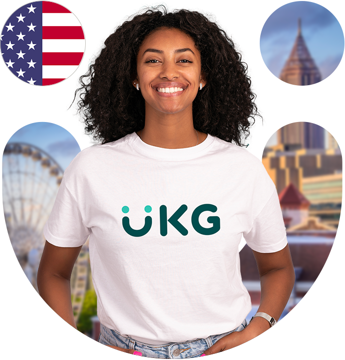 A smiling woman wearing a white shirt with the UKG logo stands in front of an American flag.